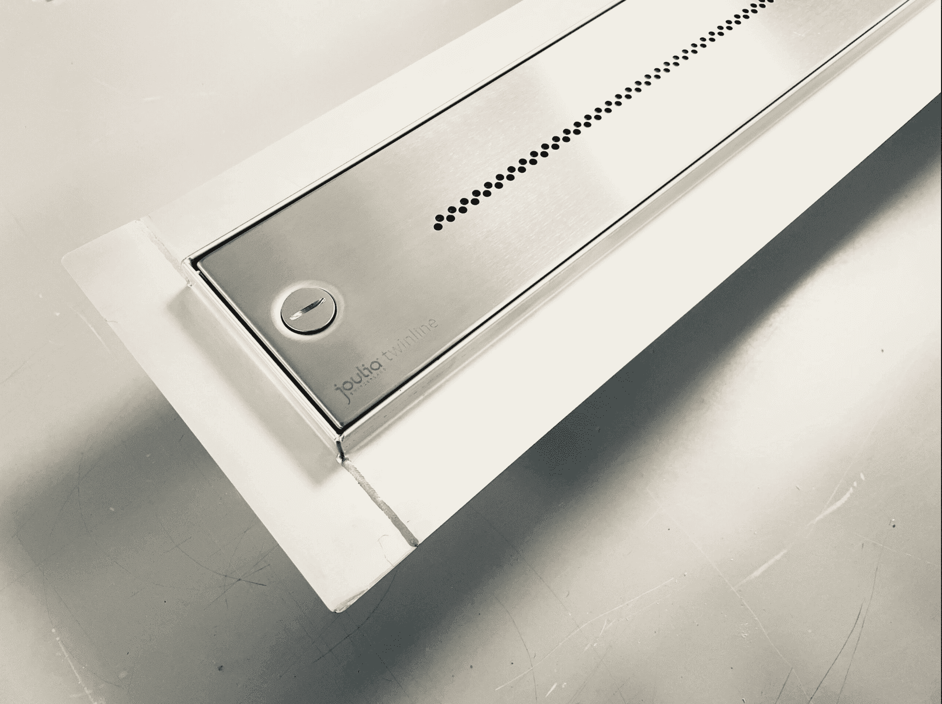 Edelstahl-Abdeckung der Twinline Duschrinne mit punktförmigem Ablaufmuster und integrierter Revisionsöffnung, bündig im Duschboden verbaut