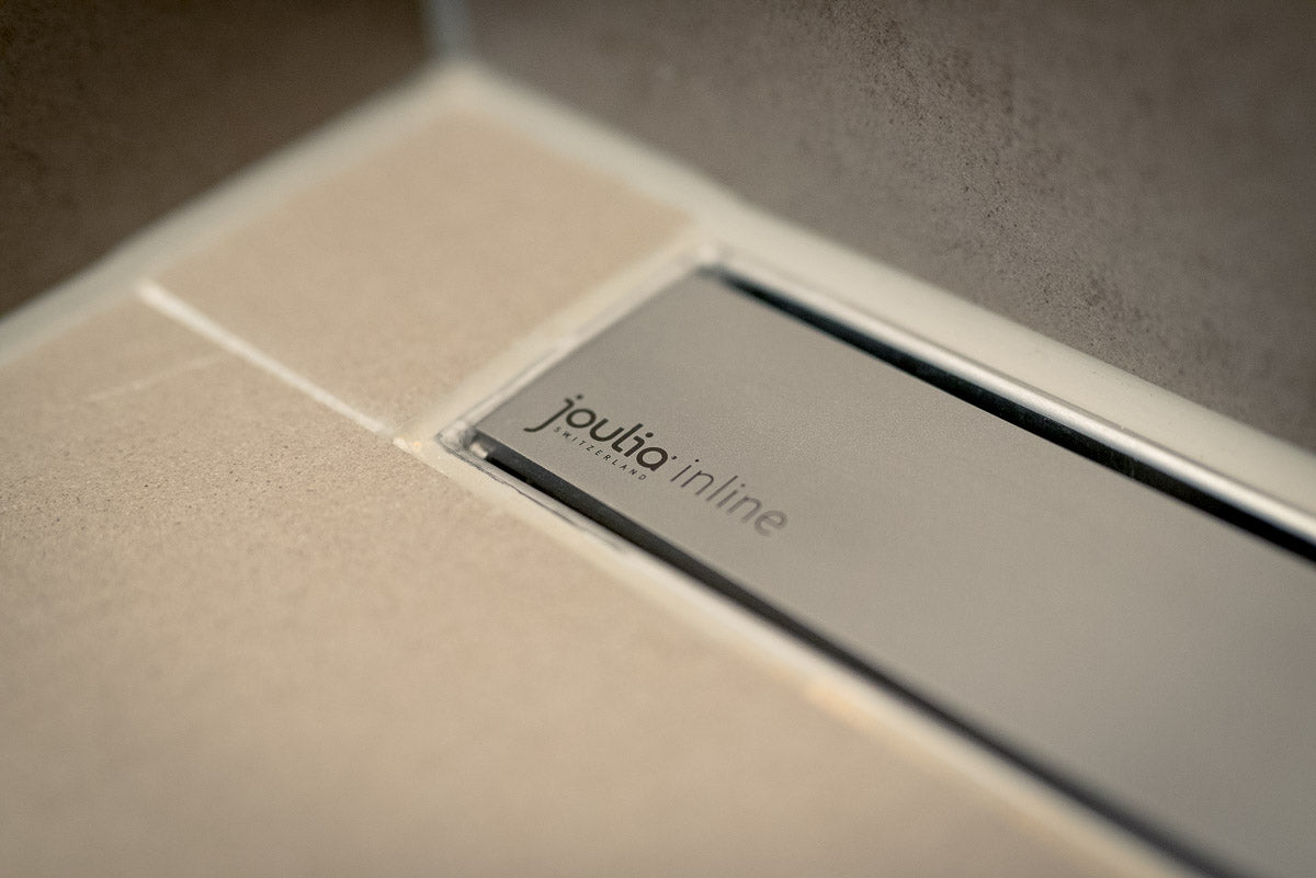 Schlanke Edelstahl-Inline-Duschrinne mit integriertem Wärmetauscher, dezent im Duschboden eingebaut