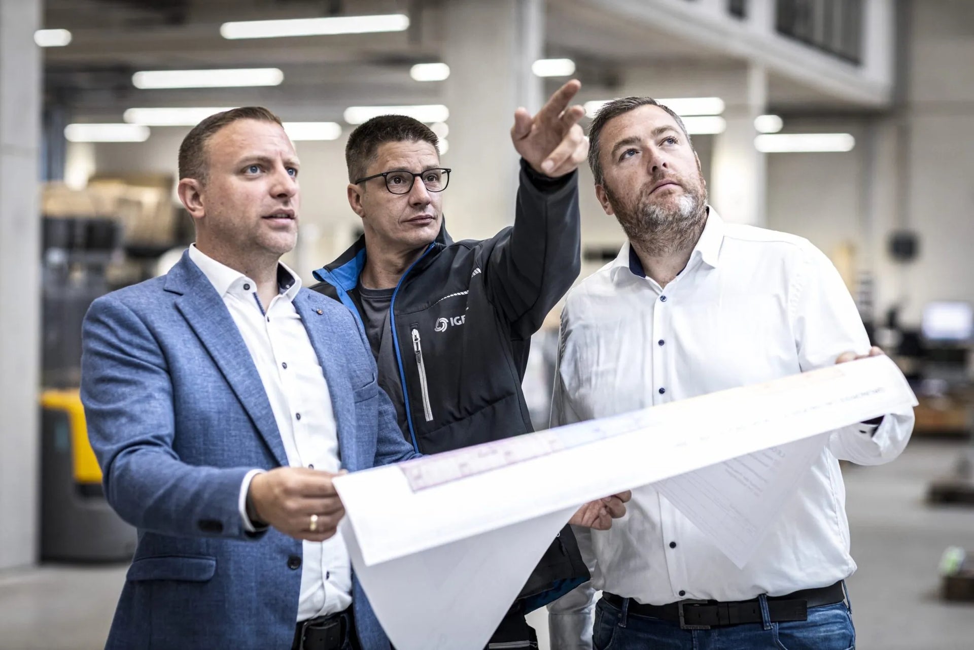 Projektbesprechung bei IGETEC Energie- und Umwelttechnik: Fachkräfte analysieren Baupläne vor Ort und stimmen energieeffiziente Gebäudetechniklösungen für Industrie-, Gewerbe- und Bauprojekte ab
