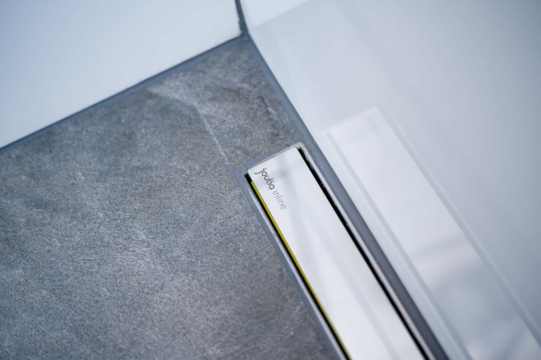 Moderne Inline-Duschrinne mit Wärmetauscher von Joulia, flächenbündig im Duschboden verbaut und kaum sichtbar