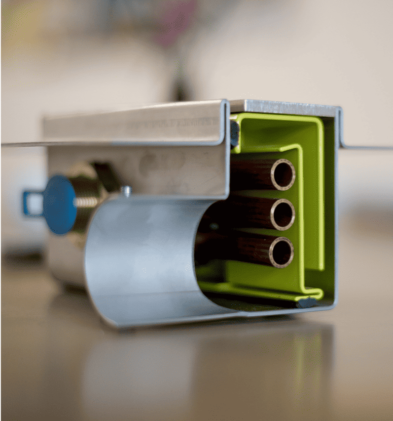 Detailansicht einer aufgeschnittenen Duschrinne mit integriertem Wärmetauscher, die das grüne Siphon und mehrere innenliegende Kupferrohre zur effizienten Wärmerückgewinnung beim Duschen zeigt