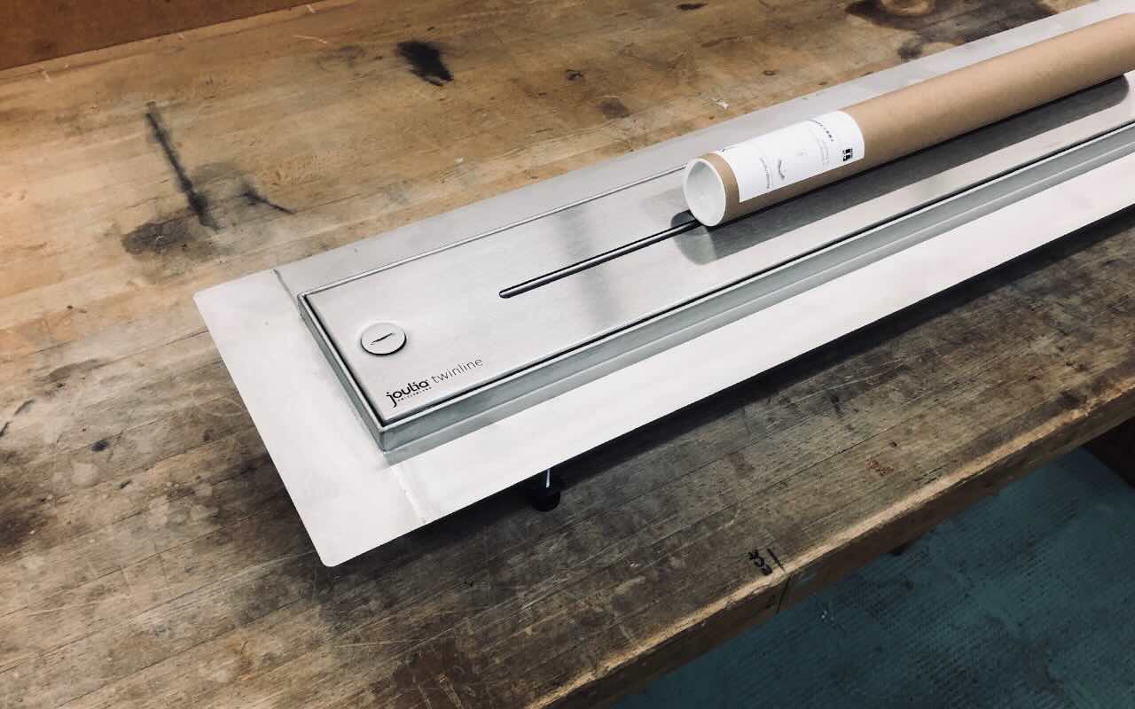 Twinline Duschrinne aus Edelstahl mit integrierter Wärmerückgewinnung, montiert auf einem Tisch  zur Demonstration von Aufbau und Design.