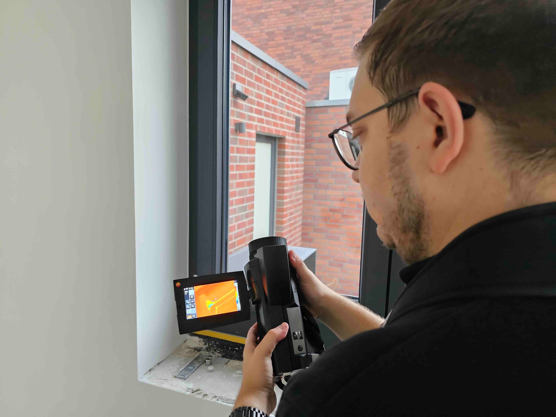 Energieberater des on. ingenieurbüros führt eine Vor-Ort-Analyse mit einer Wärmebildkamera am Fenster durch, um energetische Schwachstellen zu erkennen und fundierte Sanierungsempfehlungen zu erstellen.